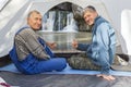 Mature male tourists are sitting in a tent and showing their thumb perfectly and admiring beautifully atysh waterfall Royalty Free Stock Photo