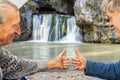 Mature male tourists are sitting in a tent and showing their thumb perfectly and admiring beautifully atysh waterfall Royalty Free Stock Photo