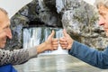 mature male tourists are sitting in a tent and showing their thumb perfectly and admiring beautifully atysh waterfall Royalty Free Stock Photo