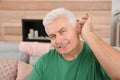 Mature man adjusting hearing aid Royalty Free Stock Photo