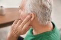 Mature man adjusting hearing aid at home Royalty Free Stock Photo