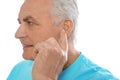 Mature man adjusting hearing aid on white Royalty Free Stock Photo