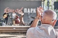 Mature man applauds, raising his hands high. Concert on summer stage in city park.