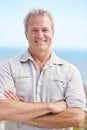 Mature, man and arms crossed in portrait on holiday at beach to travel on adventure or vacation. Smile, outdoor and Royalty Free Stock Photo