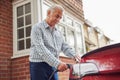 Mature Man Attaching Charging Cable To Environmentally Friendly Zero Emission Electric Car At Home Royalty Free Stock Photo