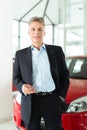 Mature man with auto in car dealership Royalty Free Stock Photo