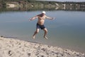 Mature man in a baseball cap and bathing shorts jumping on a san