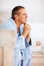 Mature man in bathrobe with hands on chin looking away. Portrait of a thoughtful mature man in bathrobe with hands on Royalty Free Stock Photo