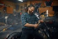 Mature man biker drinking beer in his garage workshop