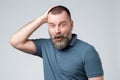 Mature man in blue t-shirt looks with frightened expression as sees something awful in front Royalty Free Stock Photo