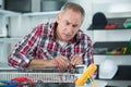 Mature man checking radiator issue with multimeter tool
