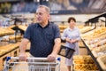 Mature man choosing bread and baking in grocery section of supermarket Royalty Free Stock Photo