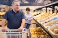 mature man choosing bread and baking in grocery section of supermarket Royalty Free Stock Photo