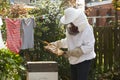 Mature Man Collecting Honey From Hive In Garden