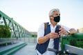 Mature man commuter with face mask and electric scooter outdoors in city, coronavirus concept. Royalty Free Stock Photo