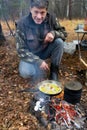 Mature man is cooking scrambled eggs on a fire Royalty Free Stock Photo