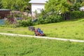 Mature man driving grass cutter in a sunny dGardener driving a riding lawn mower in a gardenay.Worker mowing grass in city park. Royalty Free Stock Photo