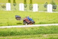 Mature man driving grass cutter in a sunny dGardener driving a riding lawn mower in a gardenay.Worker mowing grass in city park. Royalty Free Stock Photo