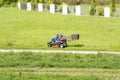 Mature man driving grass cutter in a sunny dGardener driving a riding lawn mower in a gardenay.Worker mowing grass in city park. Royalty Free Stock Photo