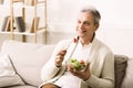 Mature man enjoying healthy salad, relaxing at home Royalty Free Stock Photo