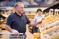 elderly retired man buying bread and pastries in grocery section of the supermarket Royalty Free Stock Photo