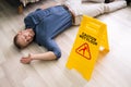 Man Falling On Wet Floor In Front Of Caution Sign Royalty Free Stock Photo