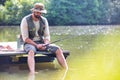 Mature man fishing in Lake while sitting on pier Royalty Free Stock Photo