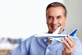 Mature man, flight and toy plane for travel, vacation and holiday planning with a smile at home. Happy, airplane model