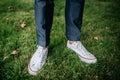 Legs of a man in a suit and white sneakers standing in the grass