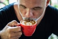 Mature man freelancer drinking coffee from red cup