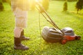 Mature man gardener cutting grass in his backyard with lawn mower on summer sunny day. Lawnmower machine for trimming grass. Royalty Free Stock Photo