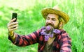 Mature man gardener relax on green grass. enjoy spring nature. summer selfie with lilac on phone. brutal ranch hipster