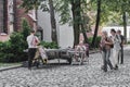 Mature man,glassblower, sitting at table in park, in process of artistic glass processing.Tourists passing by are