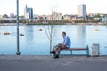 Mature man with glasses rests on bench against calm river