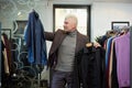 A mature man with gray hair is choosing between two shirts in a clothing store Royalty Free Stock Photo