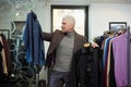A mature man with gray hair is choosing between two shirts in a clothing store Royalty Free Stock Photo