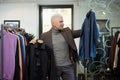 A mature man with gray hair is choosing between two shirts in a clothing store Royalty Free Stock Photo