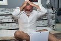 Mature man, gray-haired and bearded, wearing glasses, in pajamas, sitting on the bed, desperate with his hands on his head with Royalty Free Stock Photo