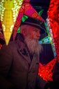 A grey bearded mature man stays among the lighted decorative stars at Christmass fair in Munich