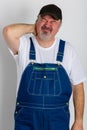 Man wearing dungarees holding his painful neck