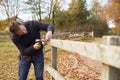 Mature Man Hammering Nail Into Repaired Fence Royalty Free Stock Photo