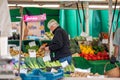 A mature man with hearing aid wearing a protective face mask shopping at an outdoor fruit and veg market stall