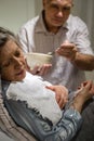 Mature man helping ill wife feeding soup Royalty Free Stock Photo