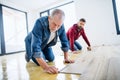 A mature man with his senior father laying vinyl flooring, a new home concept. Royalty Free Stock Photo