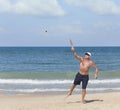 A mature man hits a ball while playing matkot on the beach