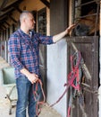 Mature man holding a surcingle and standing near horse at farm Royalty Free Stock Photo