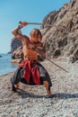 Mature Tattoo Man Holding Swords Ready To Fight on the sea background - Portrait Of A Handsome Muscular Ancient Warrior Royalty Free Stock Photo