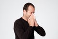 Mature man is ill from colds or pneumonia, sneezing in napkin.