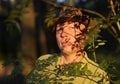 Mature man illuminated by sinshine with shadows of tree branches and leaves on him