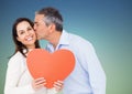 Mature man kissing woman holding a heart Royalty Free Stock Photo